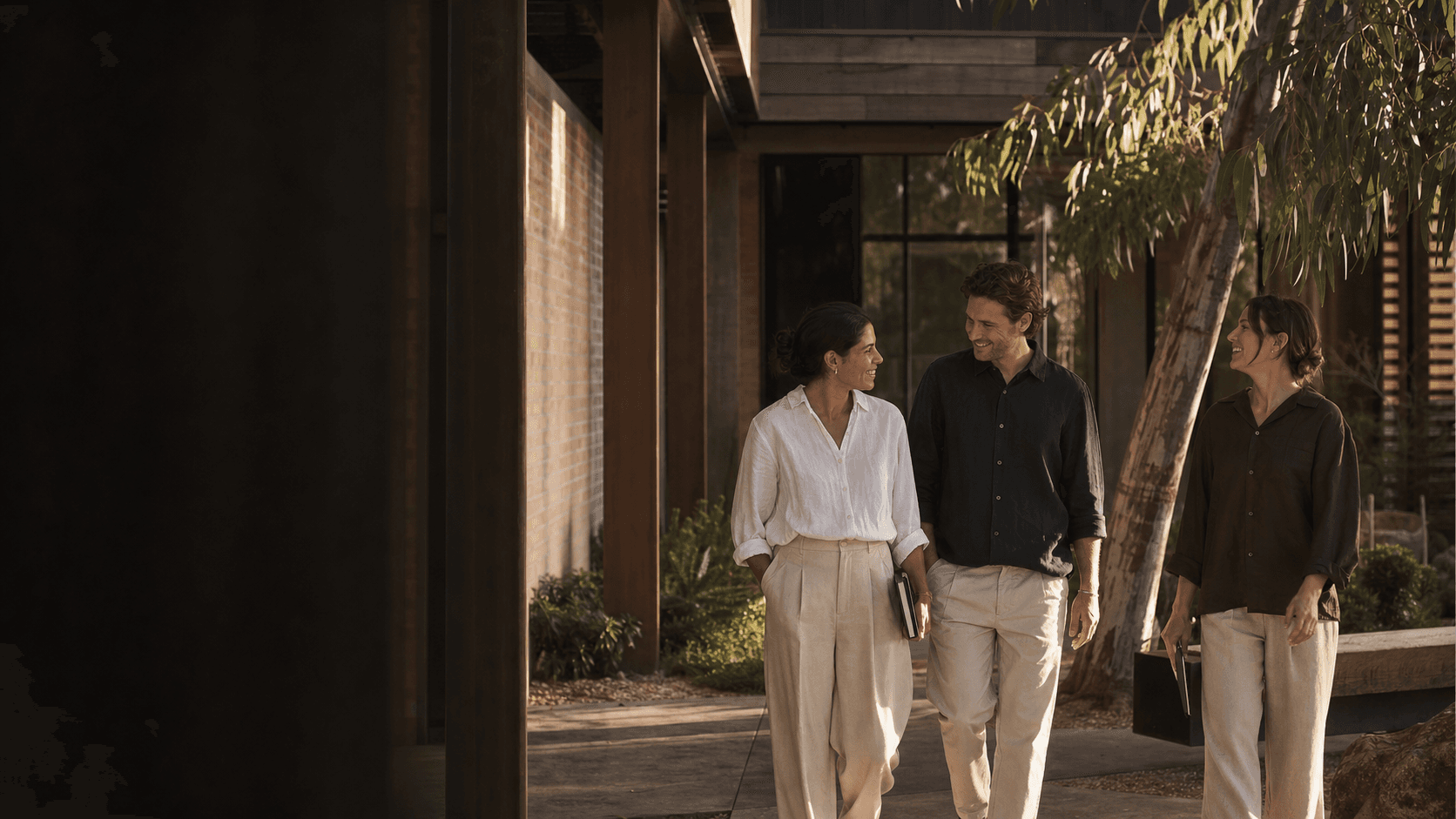 A small service-business team walking together through a landscaped studio courtyard.